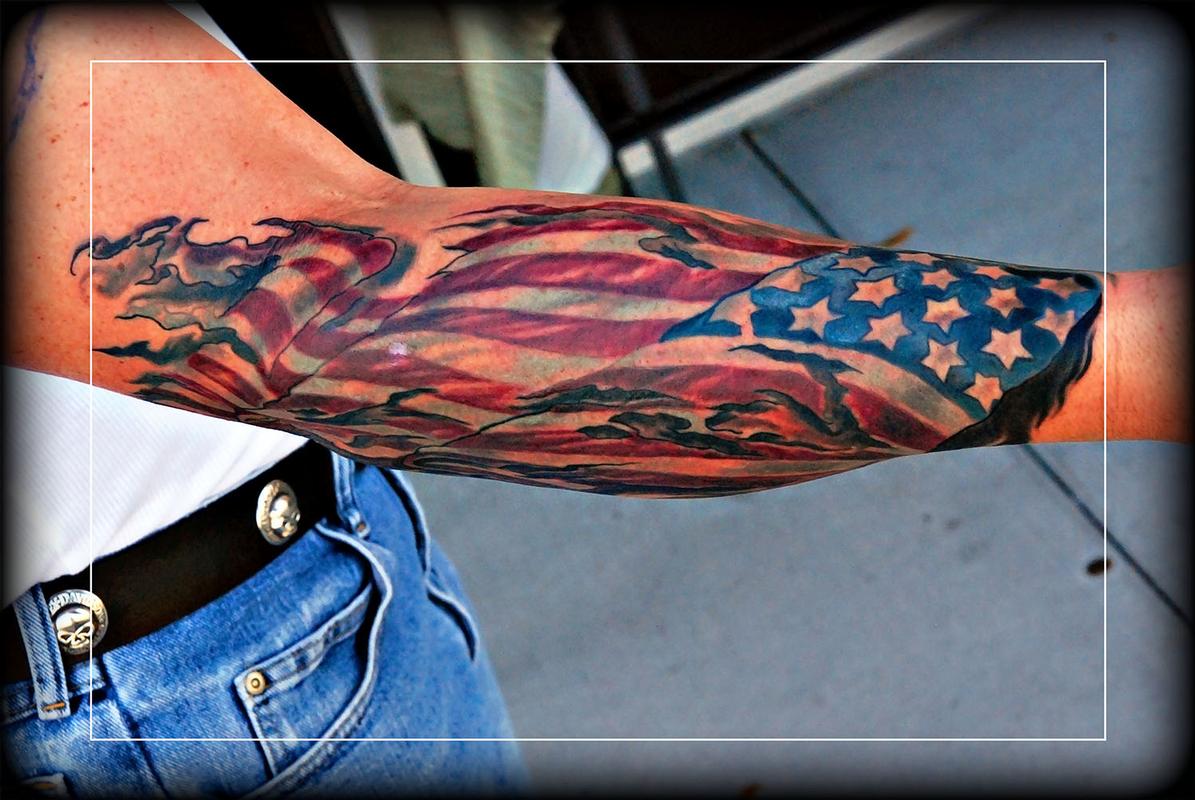 Color American flag torn skin tattoo on a forearm
